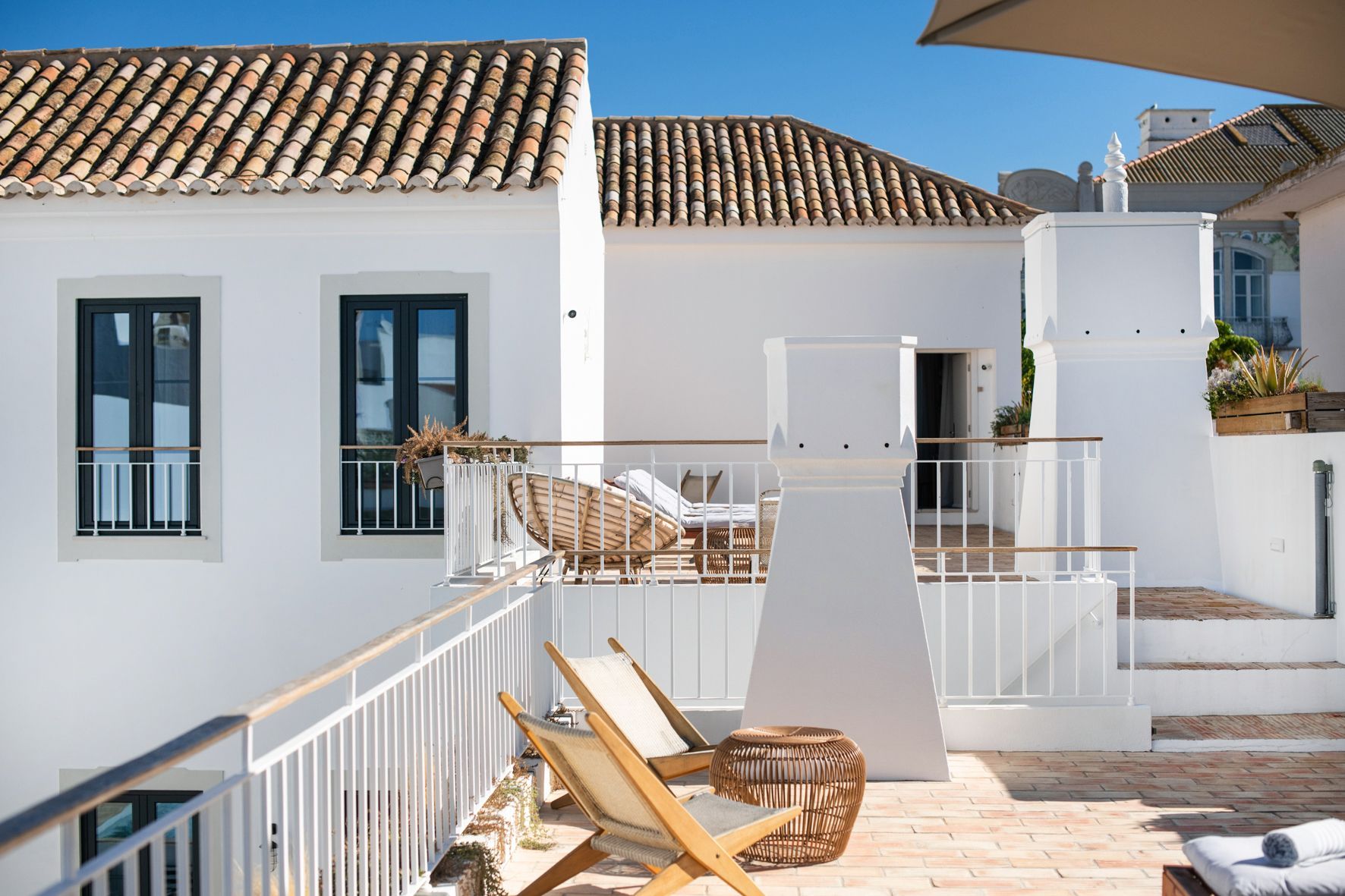 a balcony with chairs and umbrellas in front of a white building