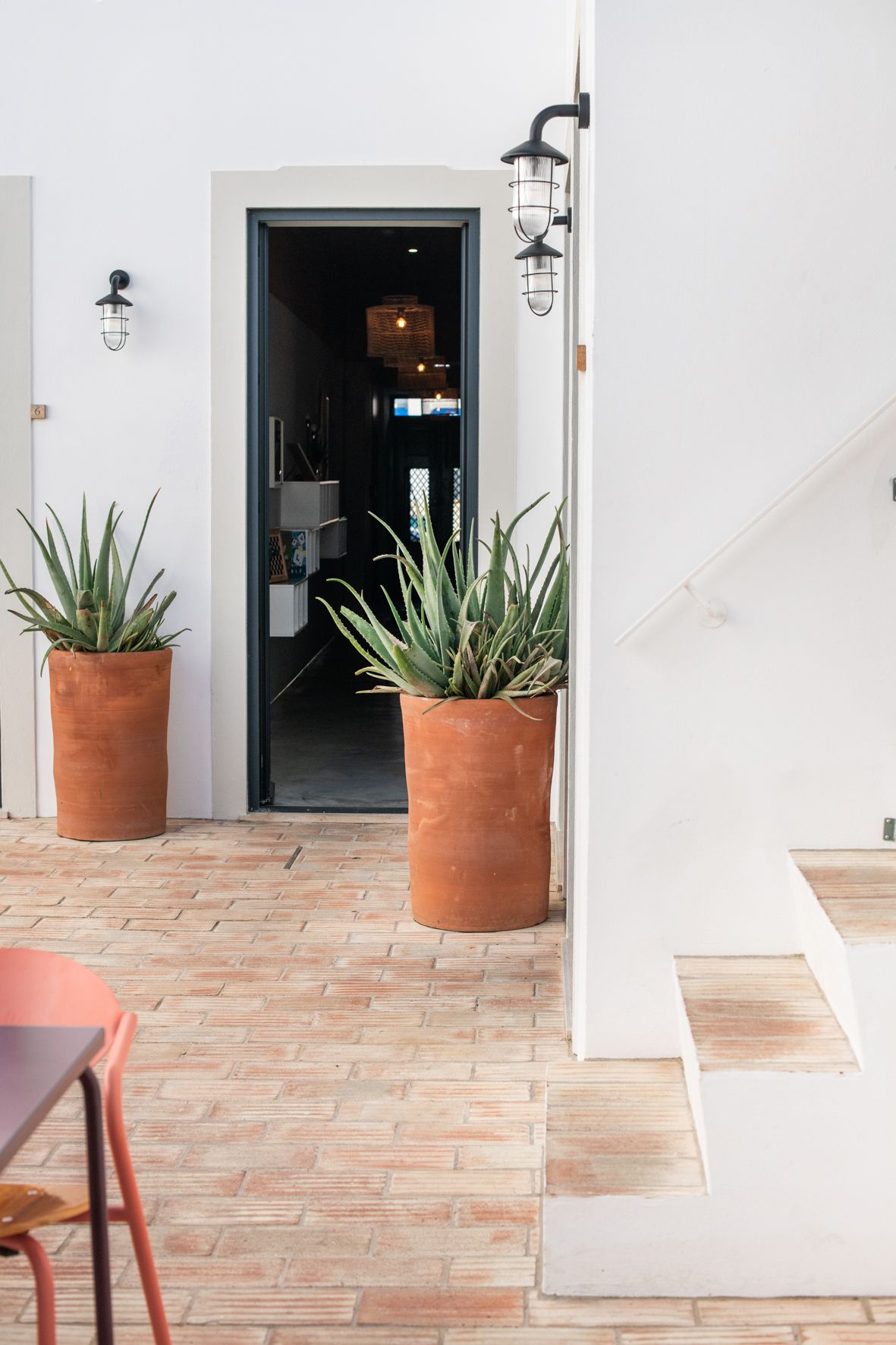 two potted plants are sitting on a brick floor in front of a door .