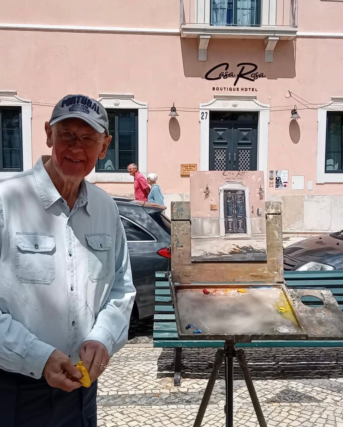 A man is standing in front of an easel with a painting on it.