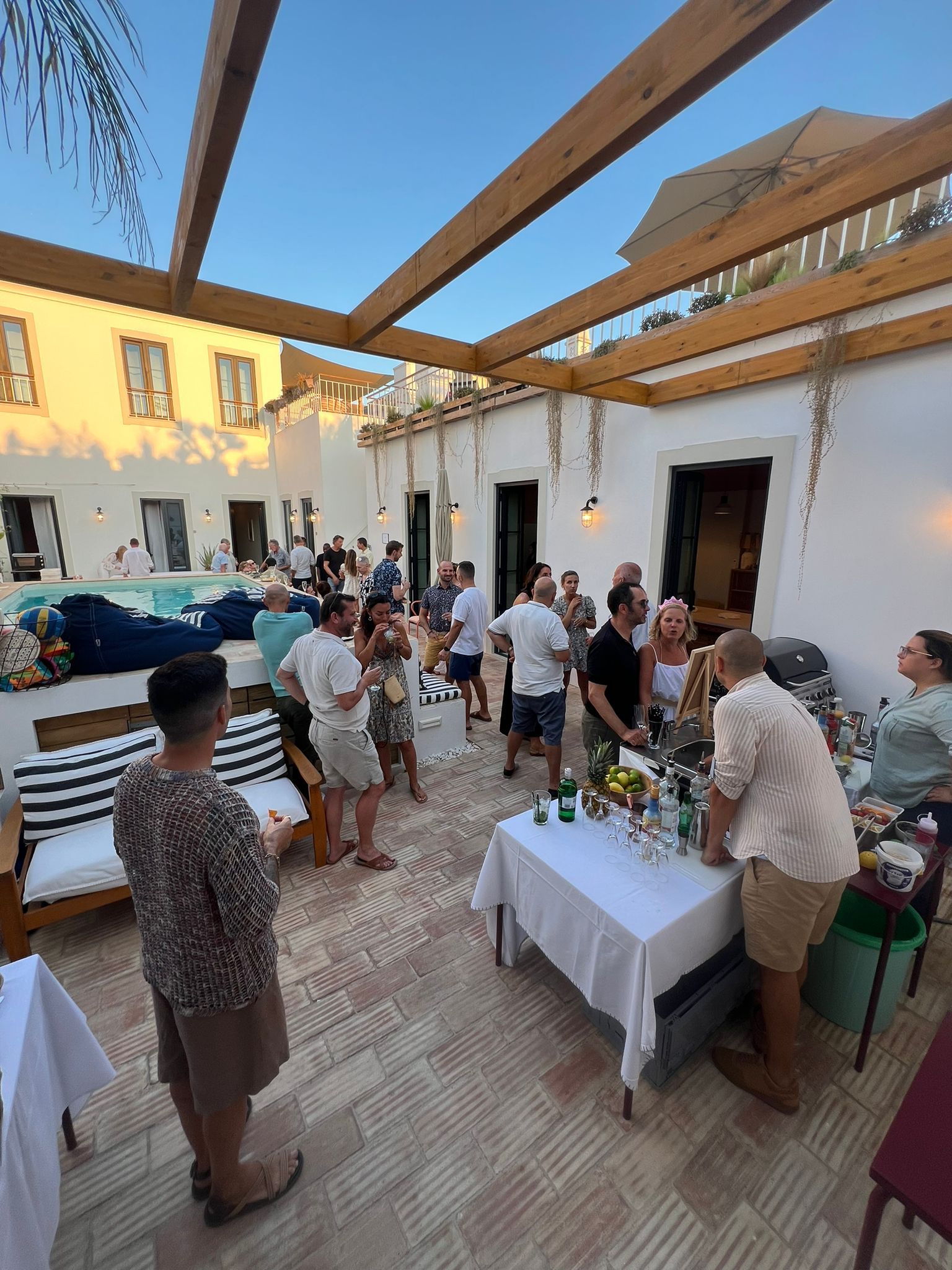 A group of people are standing around tables on a patio.