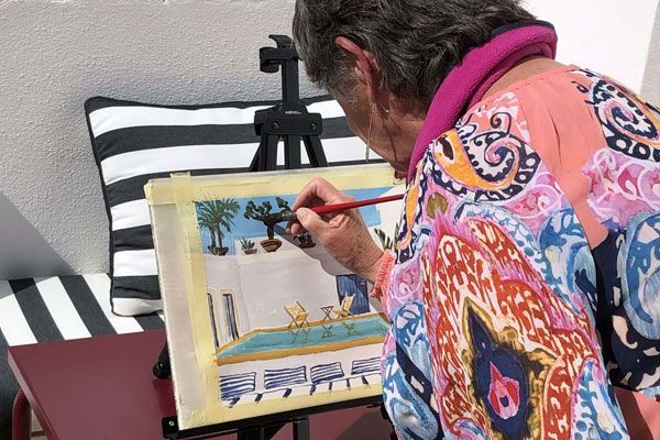 A woman is painting a picture on an easel.