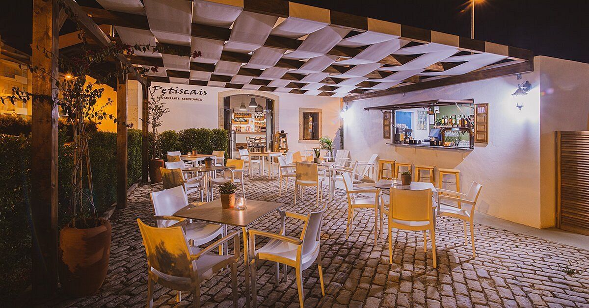A restaurant with tables and chairs outside at night.