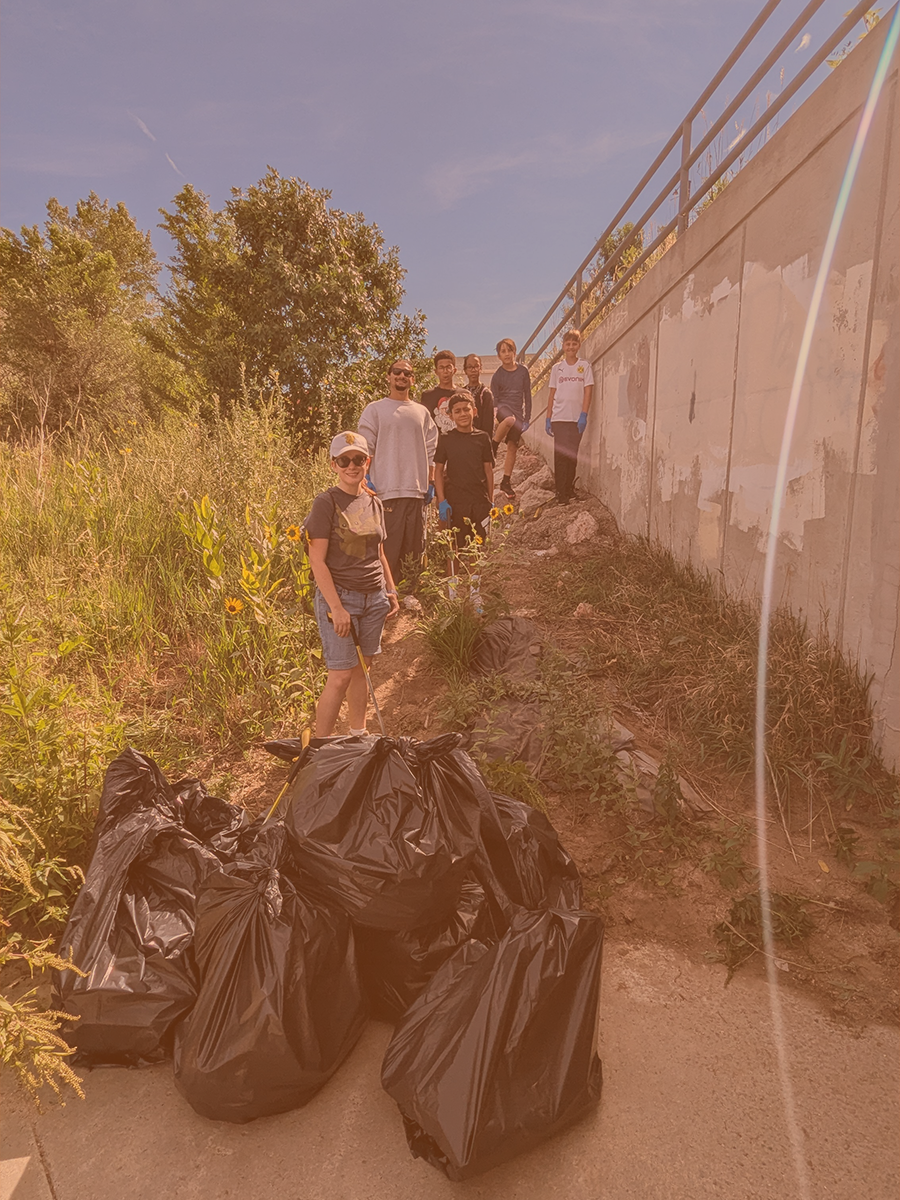 A group stands by bags of trash