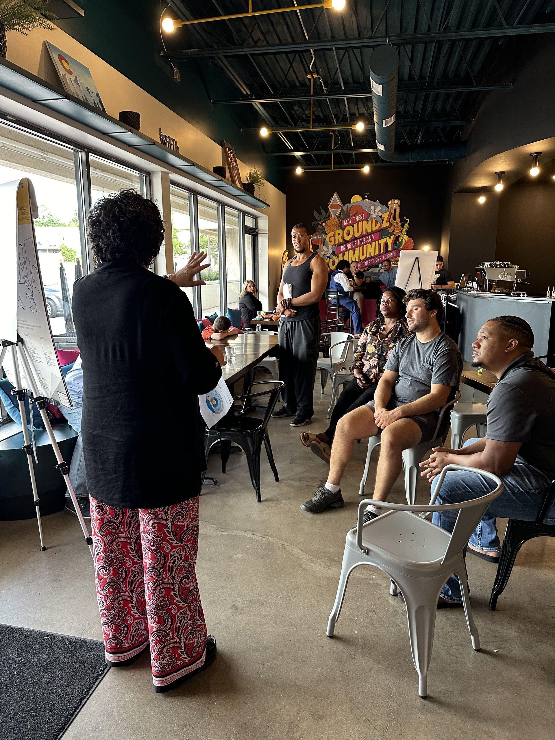 A large group of people, split up at several tables and around a large conference room, smile at the camera