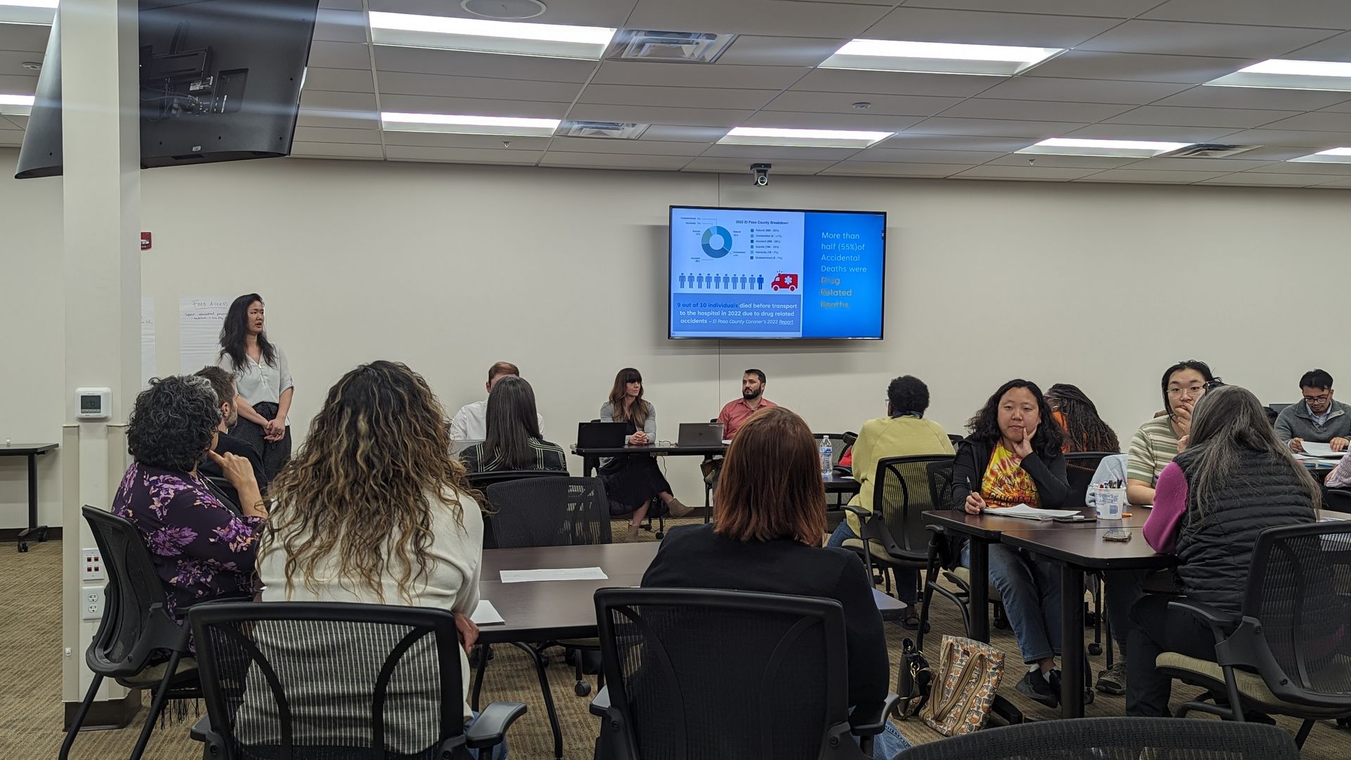 Several people in a conference room with a presentation on the screen