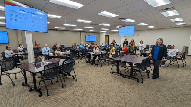 A large room filled with people sitting at tables and chairs.