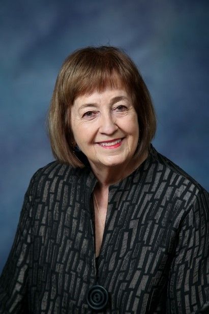 The woman is wearing a black jacket and smiling for the camera.