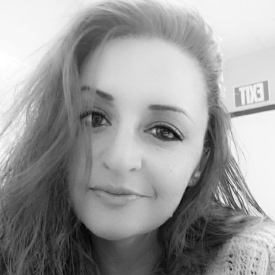 A woman with long hair is smiling in a black and white photo.