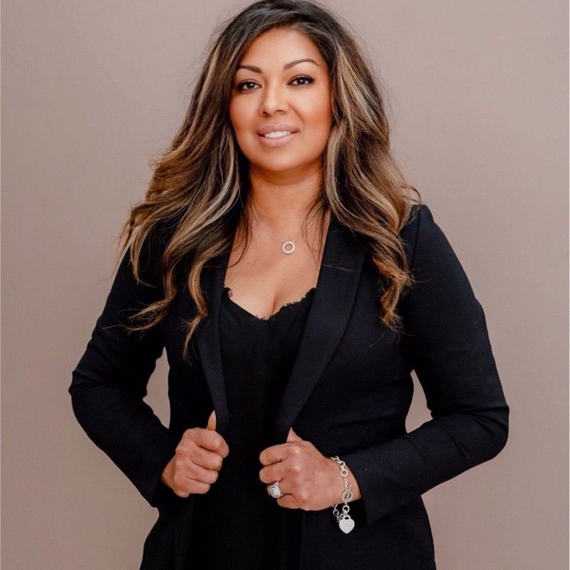 A woman is wearing a black jacket and a necklace