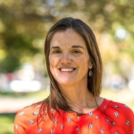 A woman in a red shirt is smiling for the camera.