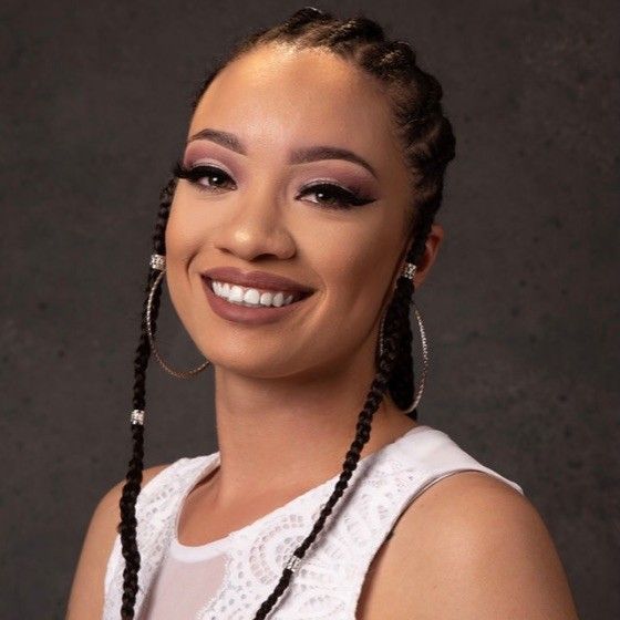 A woman with braids and hoop earrings smiles for the camera