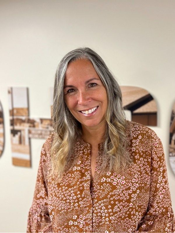 A woman in a brown floral shirt is smiling for the camera.