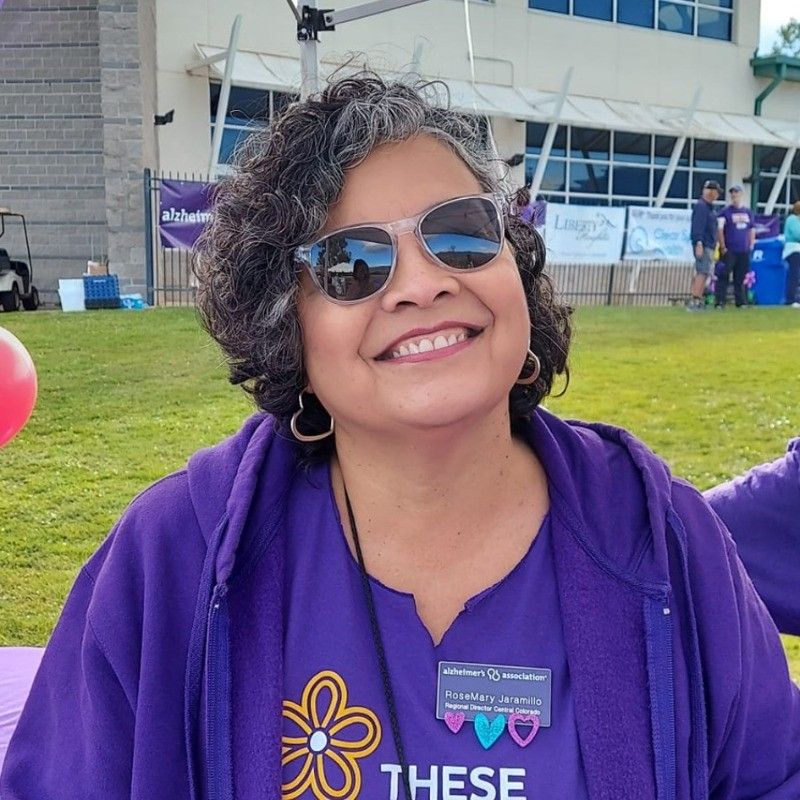 A woman wearing sunglasses and a purple shirt that says these