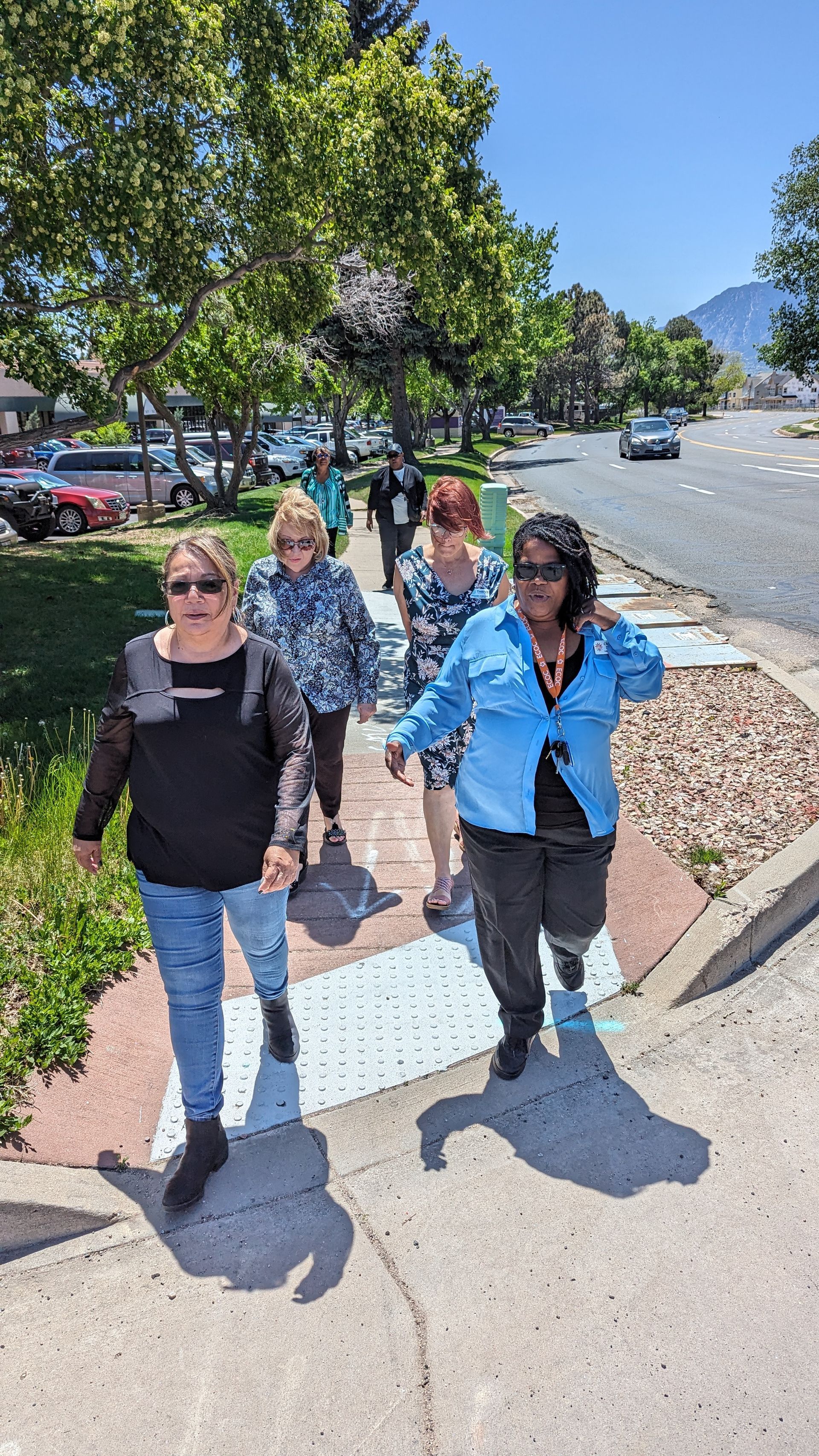 A group of women are walking down a sidewalk holding hands.