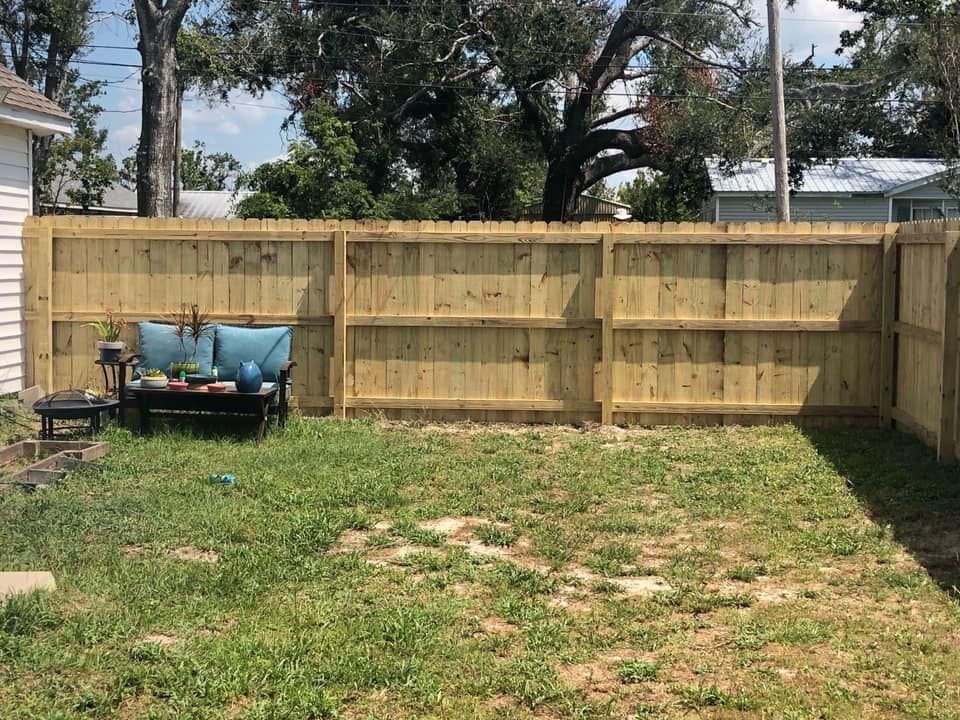 Backyard with a wooden privacy fence and a small blue wheelbarrow or cart on the left.