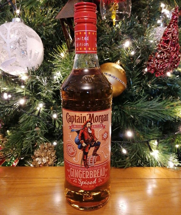 A bottle of Jackson Morgan Southern Cream, a pumpkin roll, and cinnamon sticks on a wooden table, with fall leaves in the background.