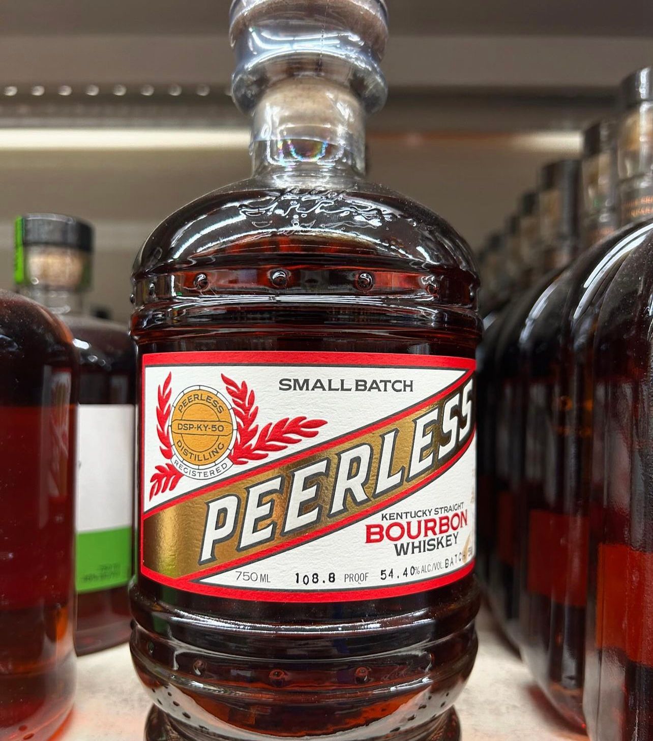 A bottle of peerless bourbon whiskey is sitting on a shelf.