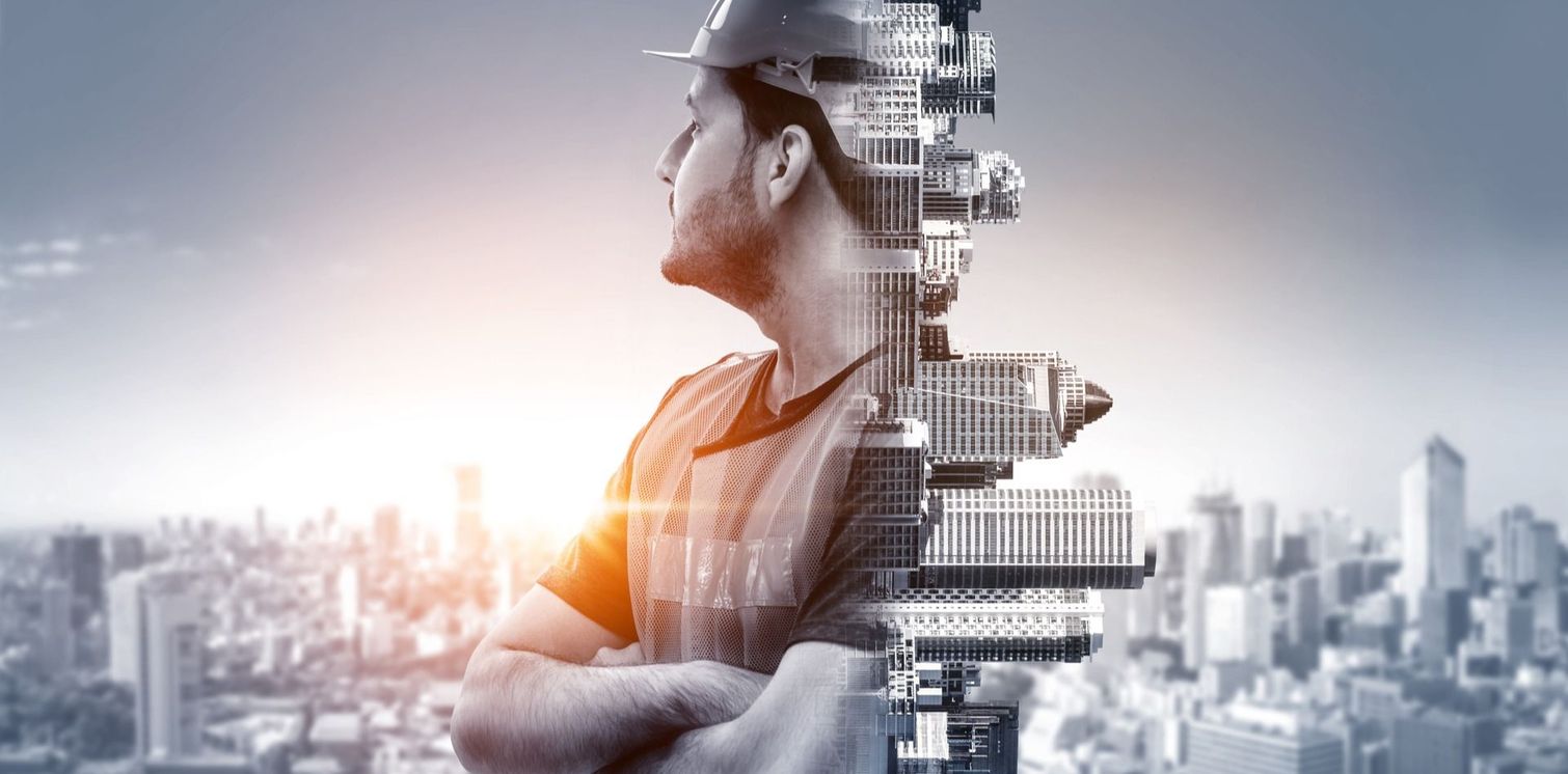 Un'immagine a doppia esposizione di un operaio edile con elmetto, sovrapposta allo skyline di una città al tramonto.