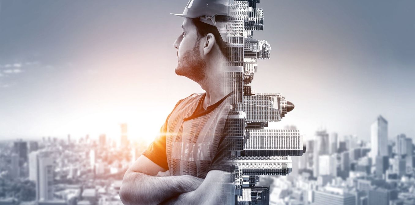 Un'immagine a doppia esposizione di un operaio edile con elmetto, sovrapposta allo skyline di una città al tramonto.