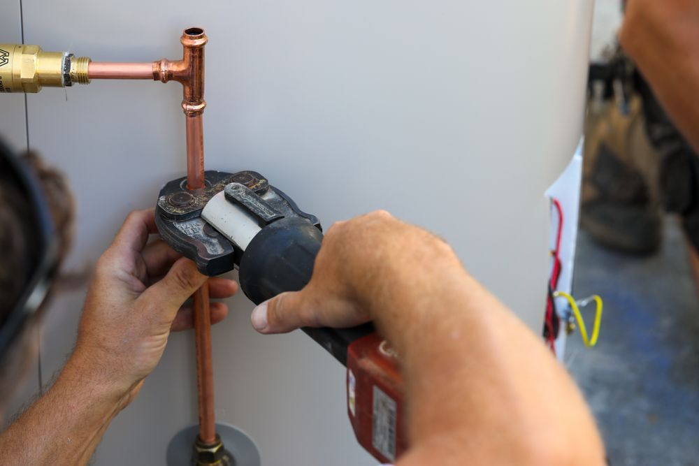 Plumber Uses a Press Tool to Connect Copper Pipes to a Water Heater — Oxplumb in Coolum Beach, QLD
