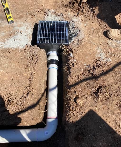 Drainage System Installation With a Grate, Pipes, and Dirt Trench — Oxplumb in Coolum Beach, QLD