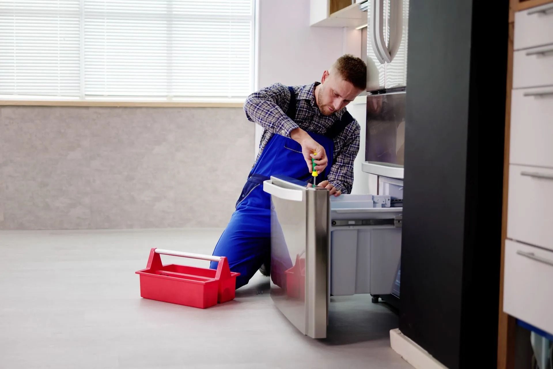 A Person Using a Screwdriver to Repair a Stainless Steel Refrigerator — Central Coast Washing Machines & Refrigerator Repairs in San Remo, NSW