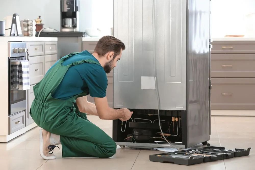 A Technician Repairs the Back of a Stainless Steel Refrigerator — Central Coast Washing Machines & Refrigerator Repairs in San Remo, NSW