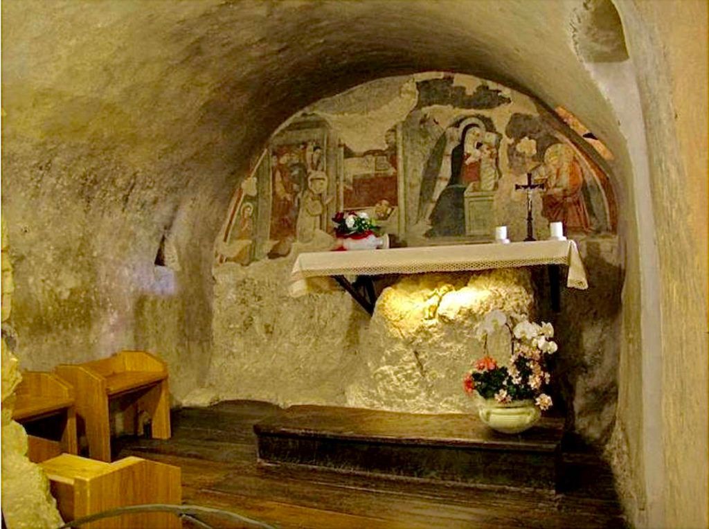 A church with a painting on the wall and a table with flowers on it.