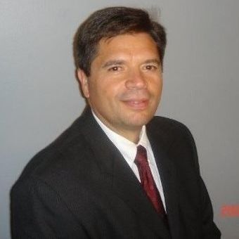 A man in a suit and tie is sitting in front of a wall.