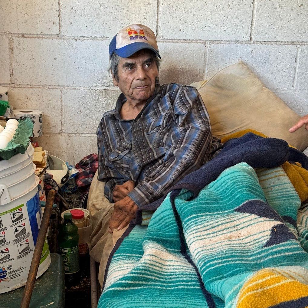 A man wearing a red bull hat is sitting on a bed