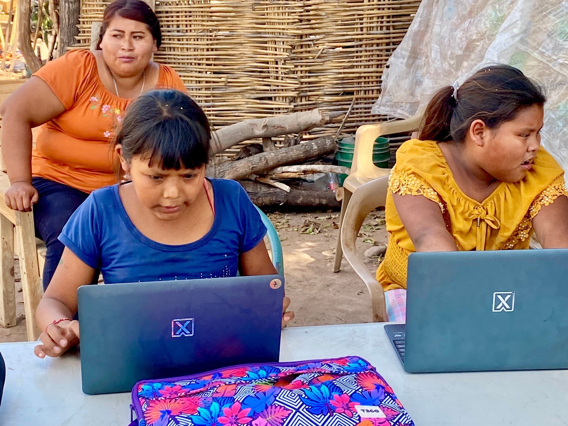 Three women are sitting at a table using laptops.