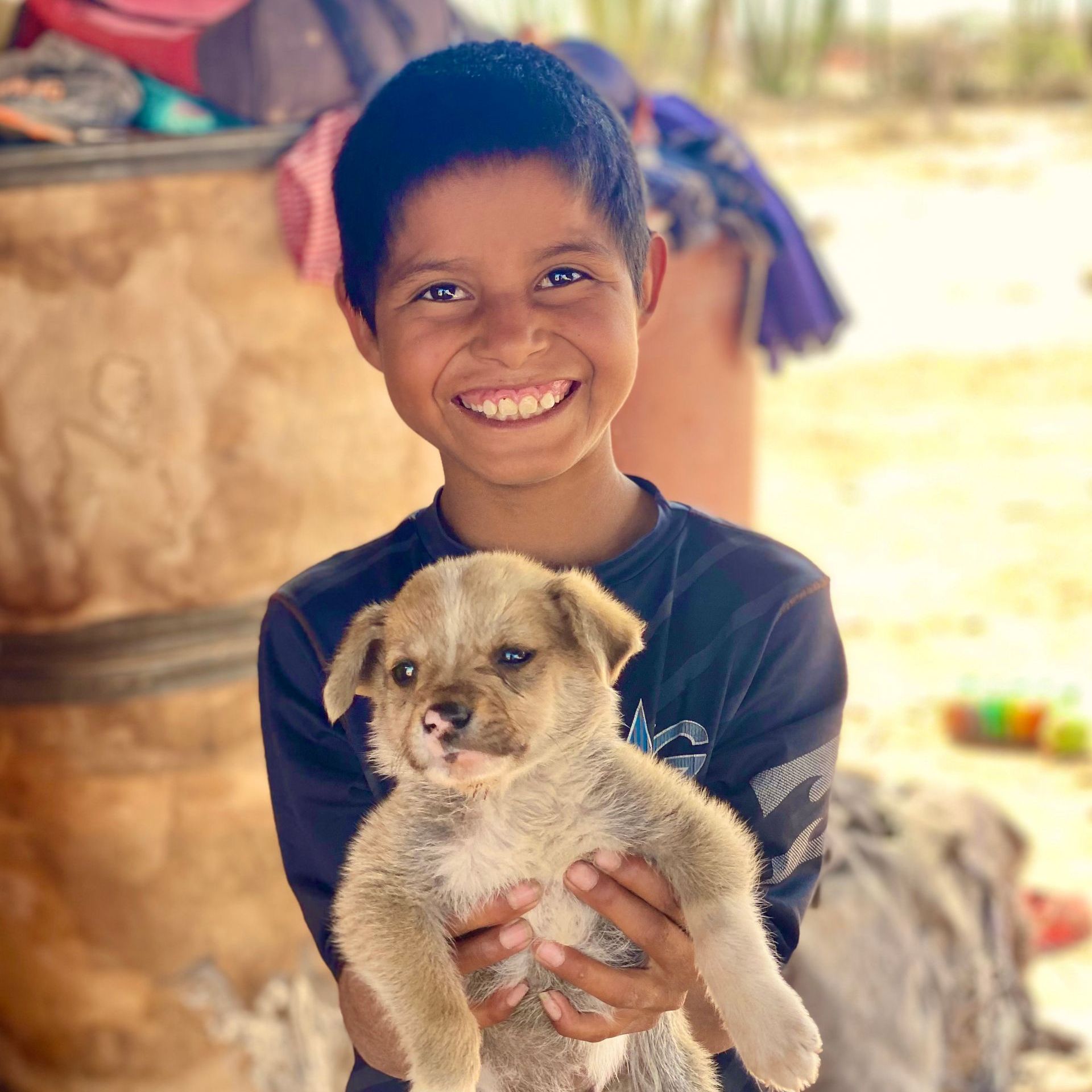 A young boy is holding a puppy and smiling for the camera