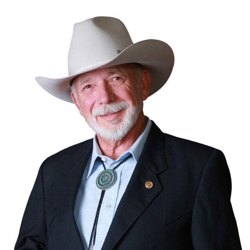 A man in a suit and cowboy hat is smiling