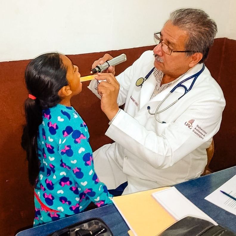 A doctor examines a little girl 's throat with a stethoscope