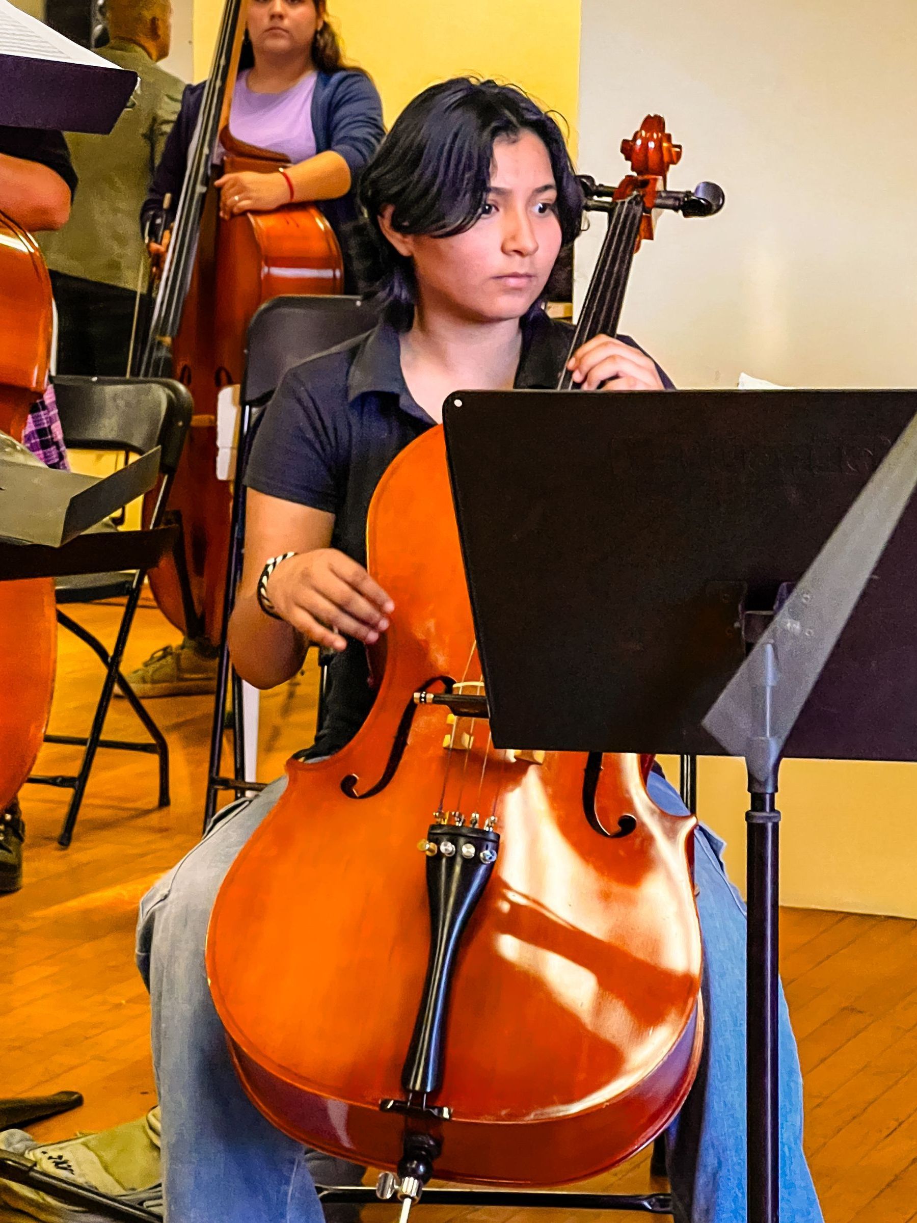 A woman is playing a cello in an orchestra