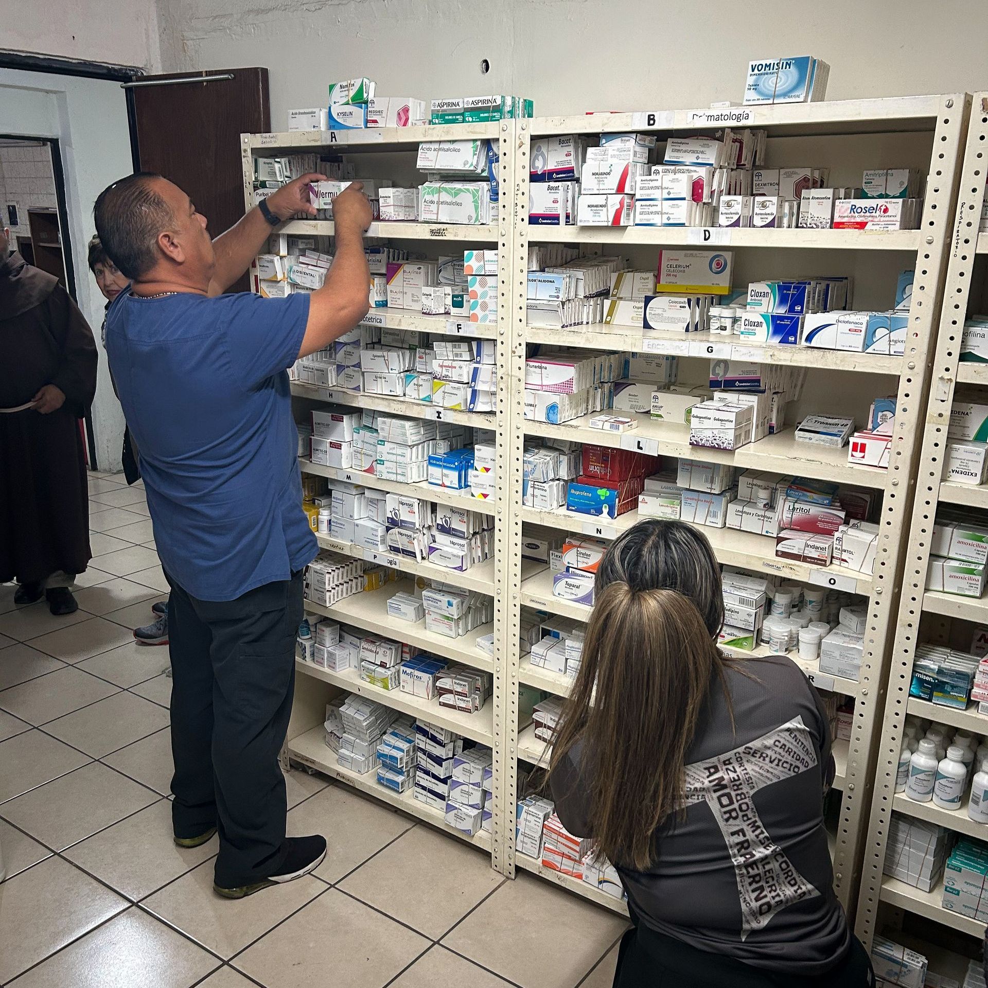 A man in a blue shirt is looking at a shelf in a pharmacy