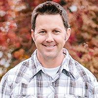 A man in a plaid shirt is smiling for the camera.