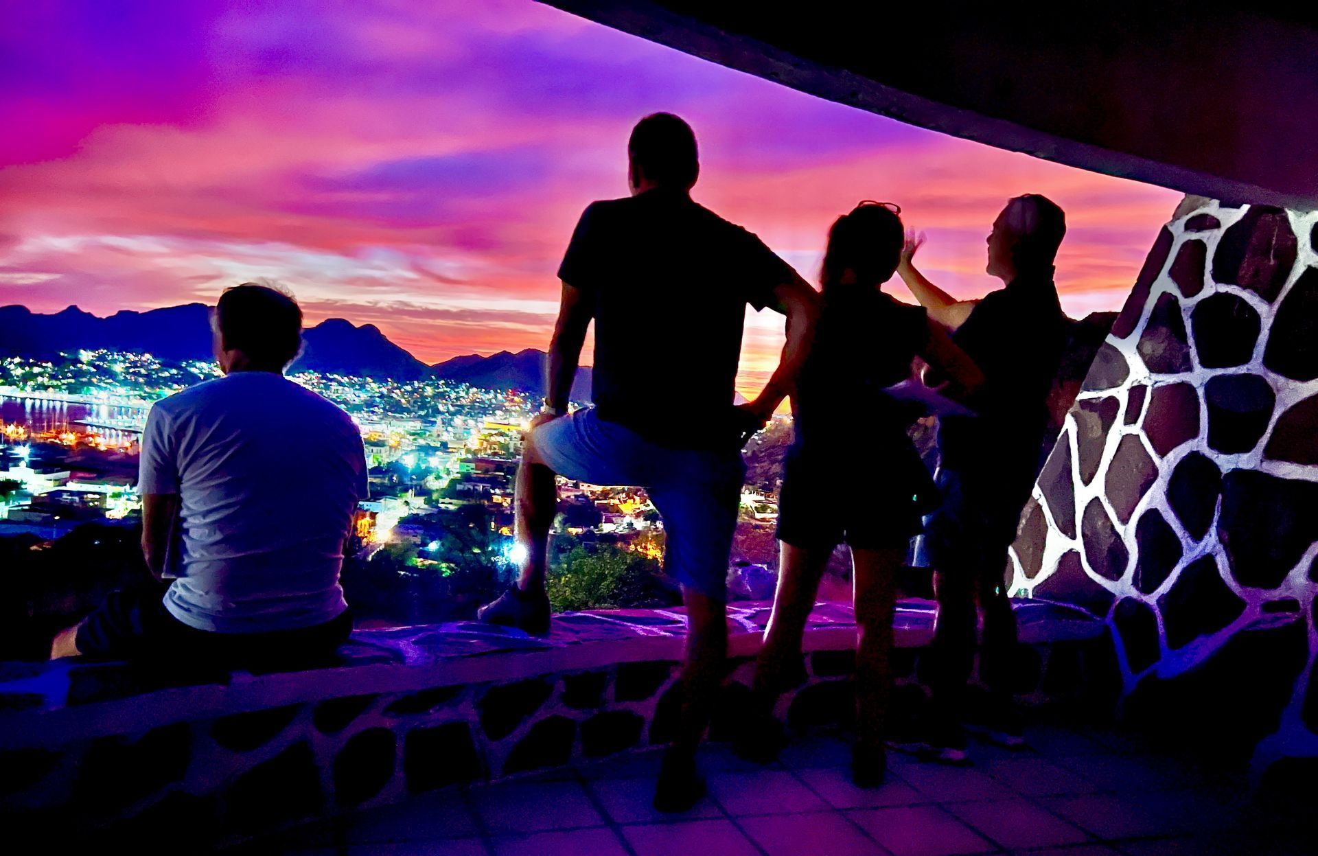 A group of people are looking at a sunset over a city.