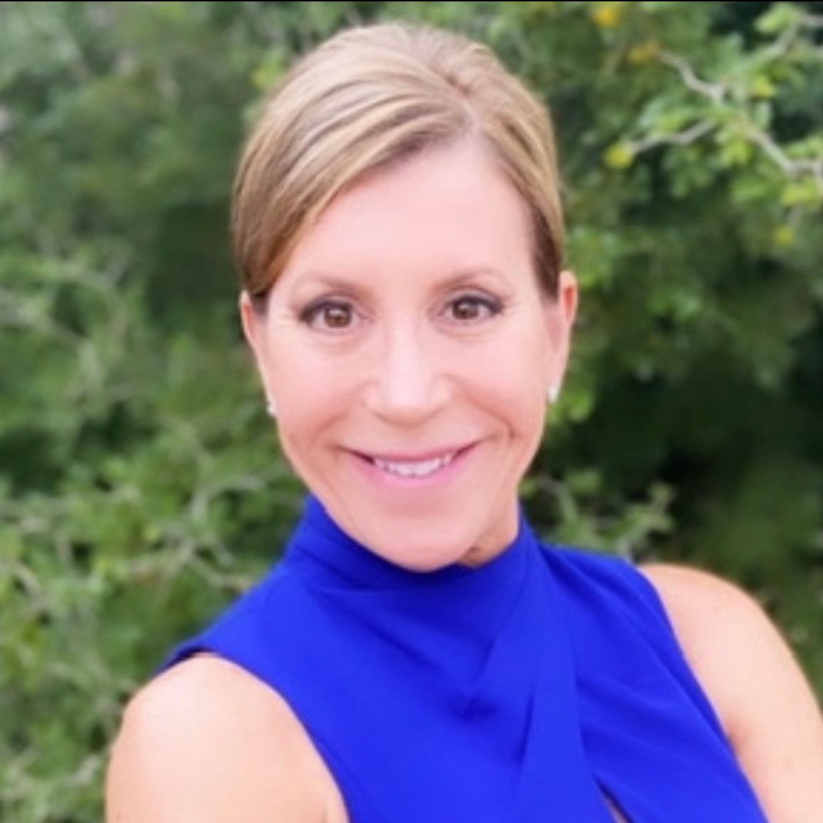 A woman in a blue shirt is smiling for the camera.