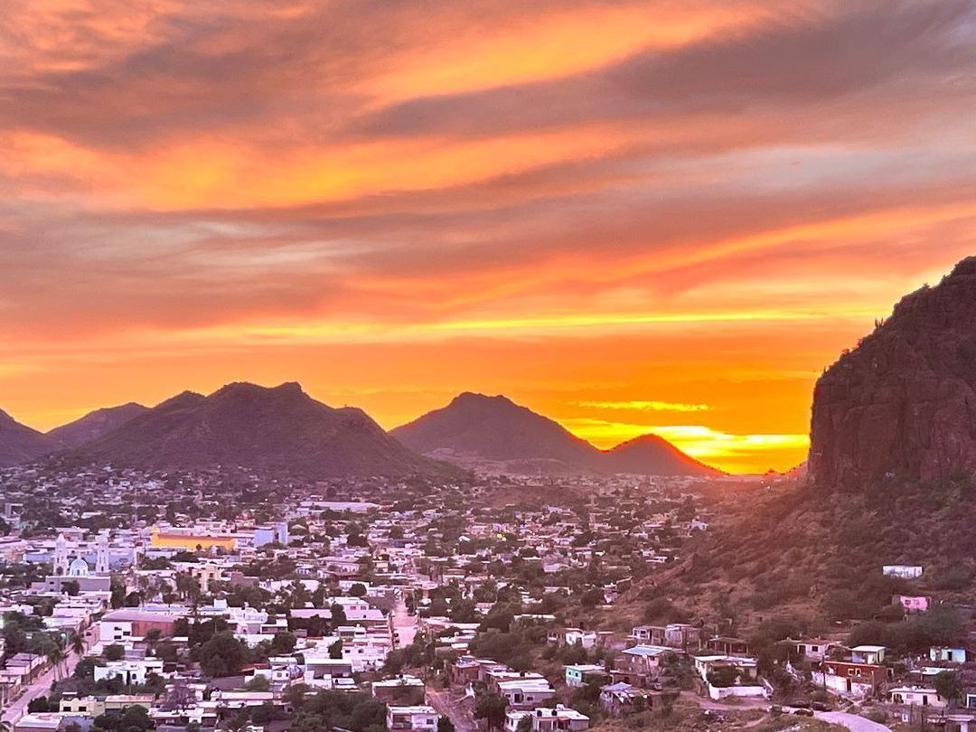 A sunset over a city with mountains in the background