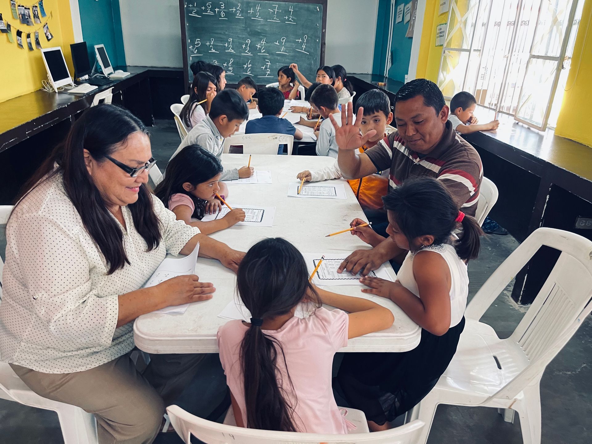 A group of children are sitting at tables in a classroom.