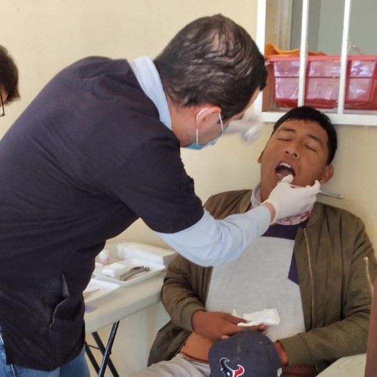 A man wearing a texas hat is being examined by a dentist