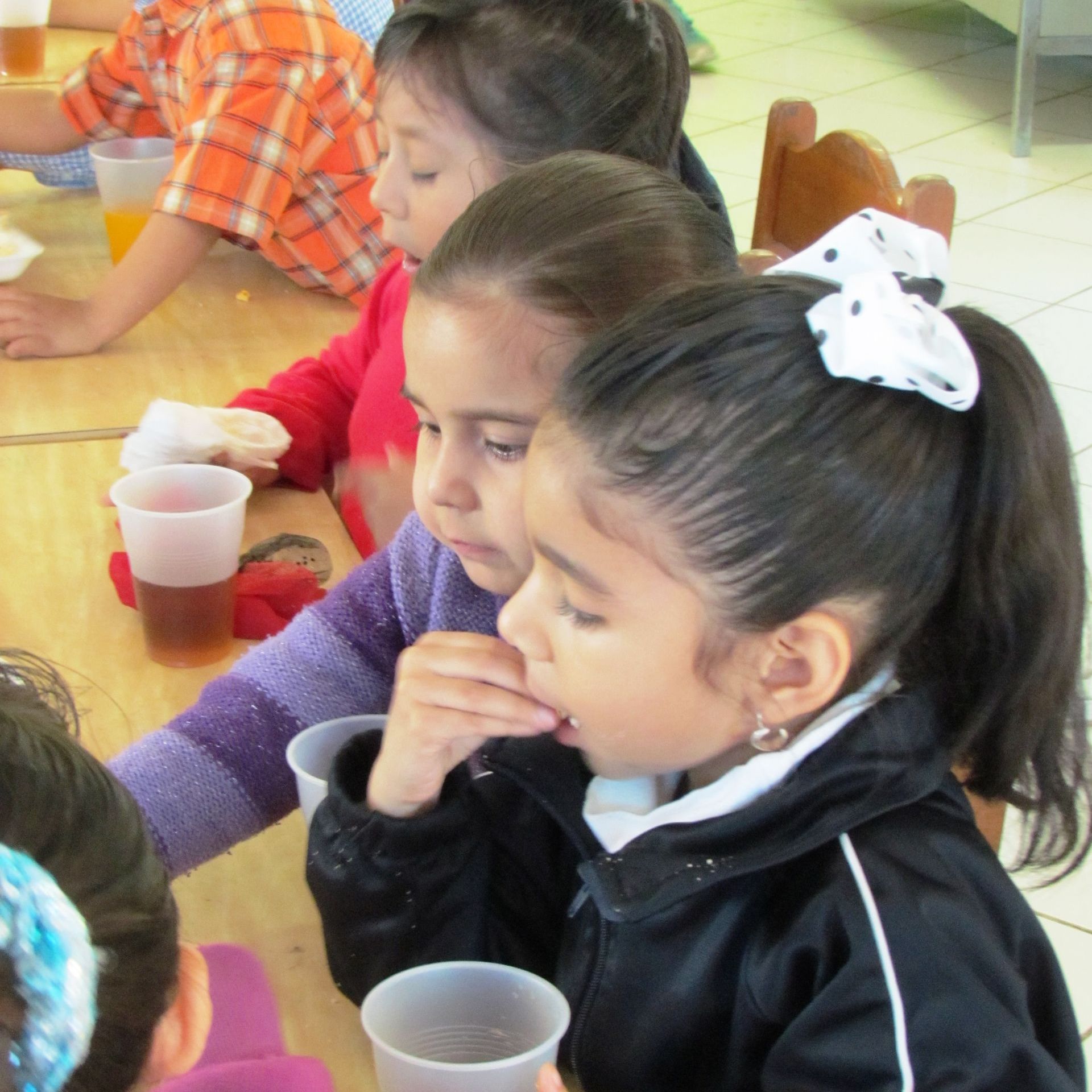 A group of children are sitting at a table drinking from plastic cups