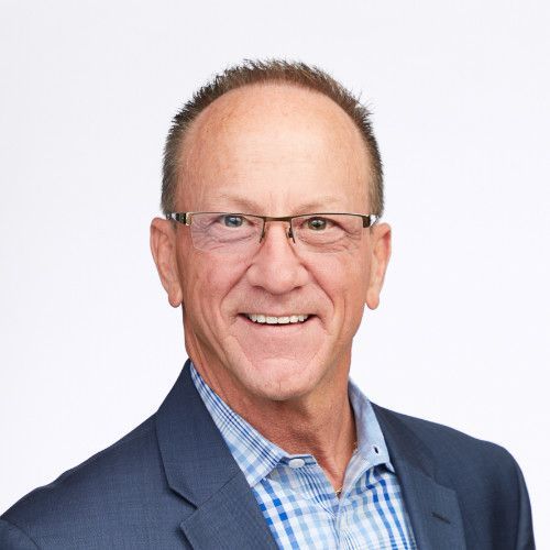 A man in a suit and glasses is smiling for the camera.