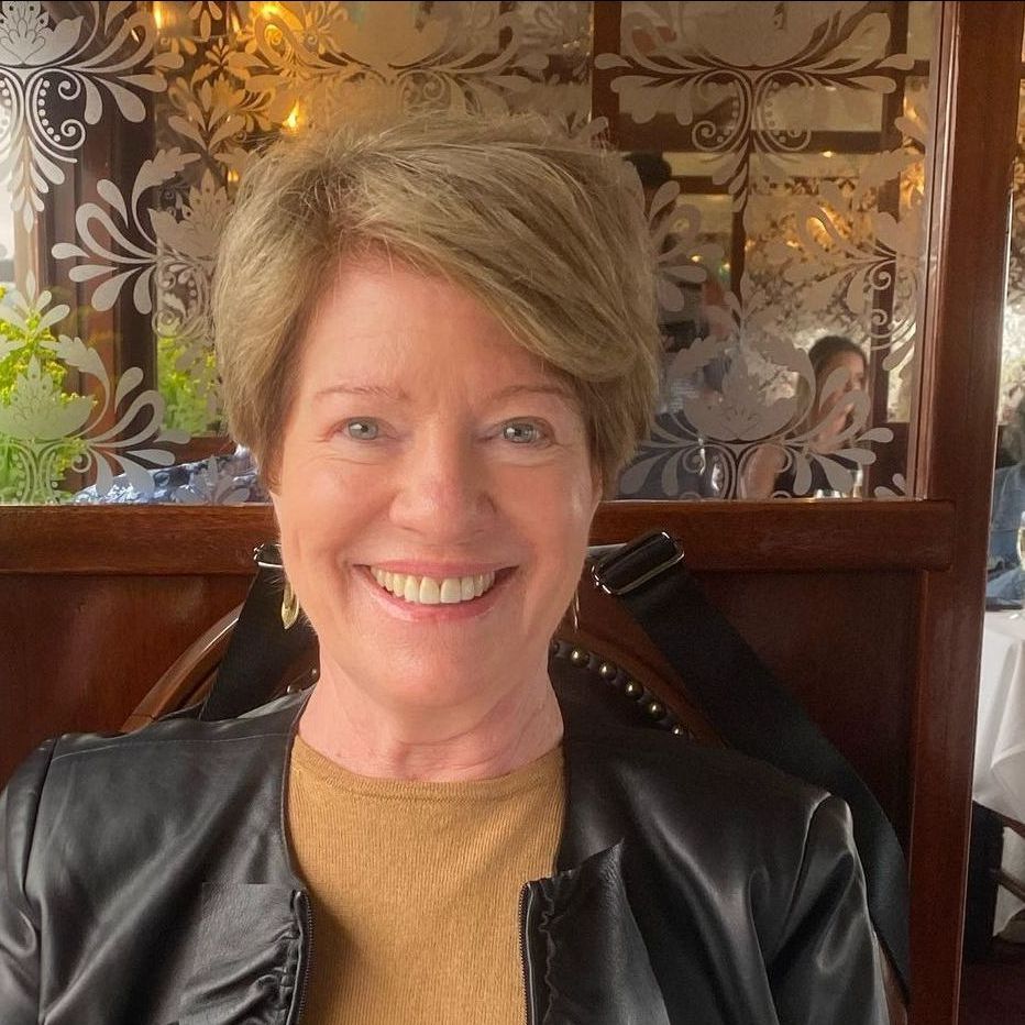 A woman in a black leather jacket is smiling in a restaurant