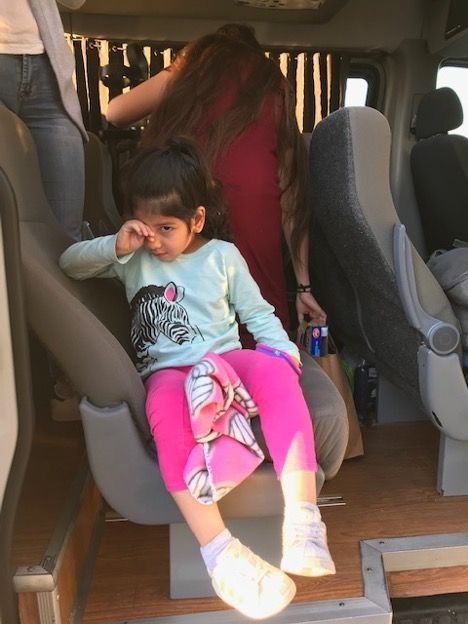 A little girl is sitting in the back seat of a van