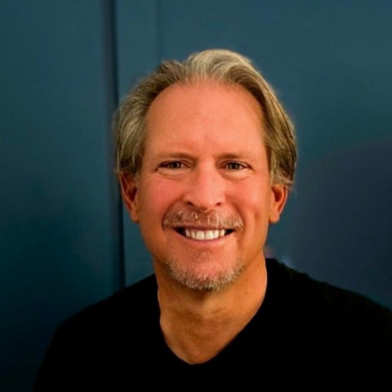 A man with a beard is smiling for the camera while wearing a black shirt.