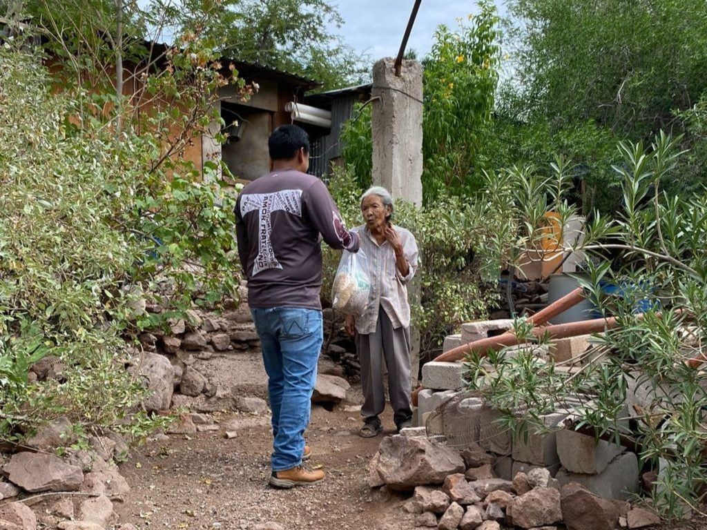 A man is giving a bag of food to an elderly woman.