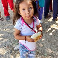 A little girl is holding a piece of bread in her hands.