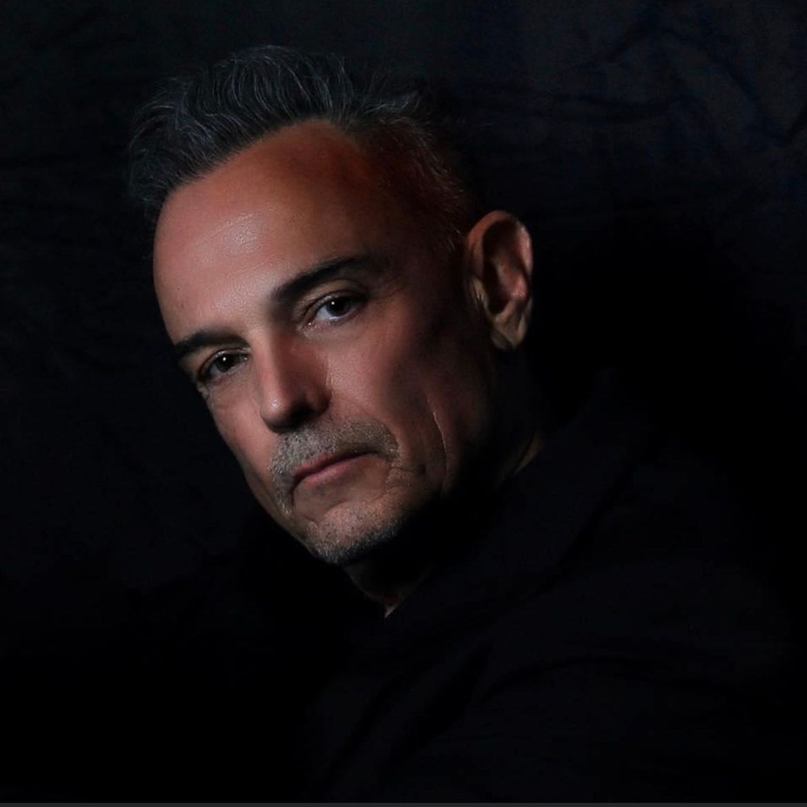 A close up of a man 's face with a dark background